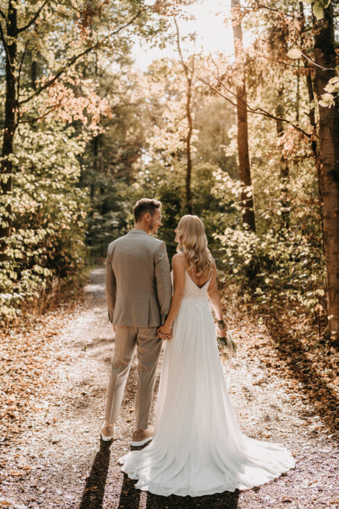 Hochzeitsfotoshooting, Brautpaar mit Blick in den Wald mit Rückenansicht