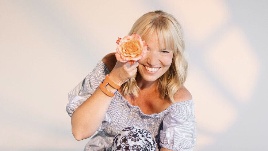 Sängerin mit einzelner orangefarbener Rose vor dem Auge im Blau weißen Kleid