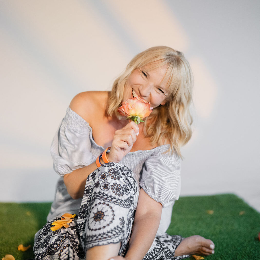 Jutta Mesch mit Blume vor dem Gesicht im blauen Kleid