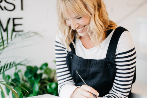 Jutta Mesch Traurednerin mit Rednermappe sitzend auf Treppen in Latzhose und Ringelshirt